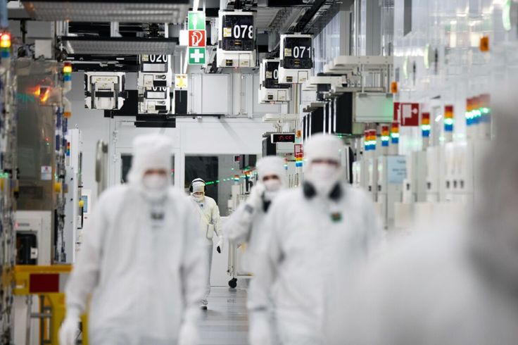 Technicians working in a semiconductor cleanroom environment with full protective suits