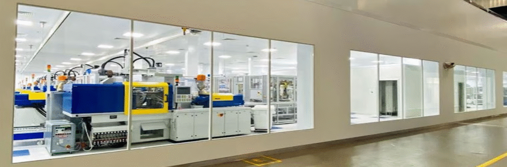 Technicians working inside a medical device cleanroom wearing full gowning suits in a controlled, particle-free environment